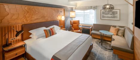 A hotel room with a large bed, a sofa, a small table, and a desk.