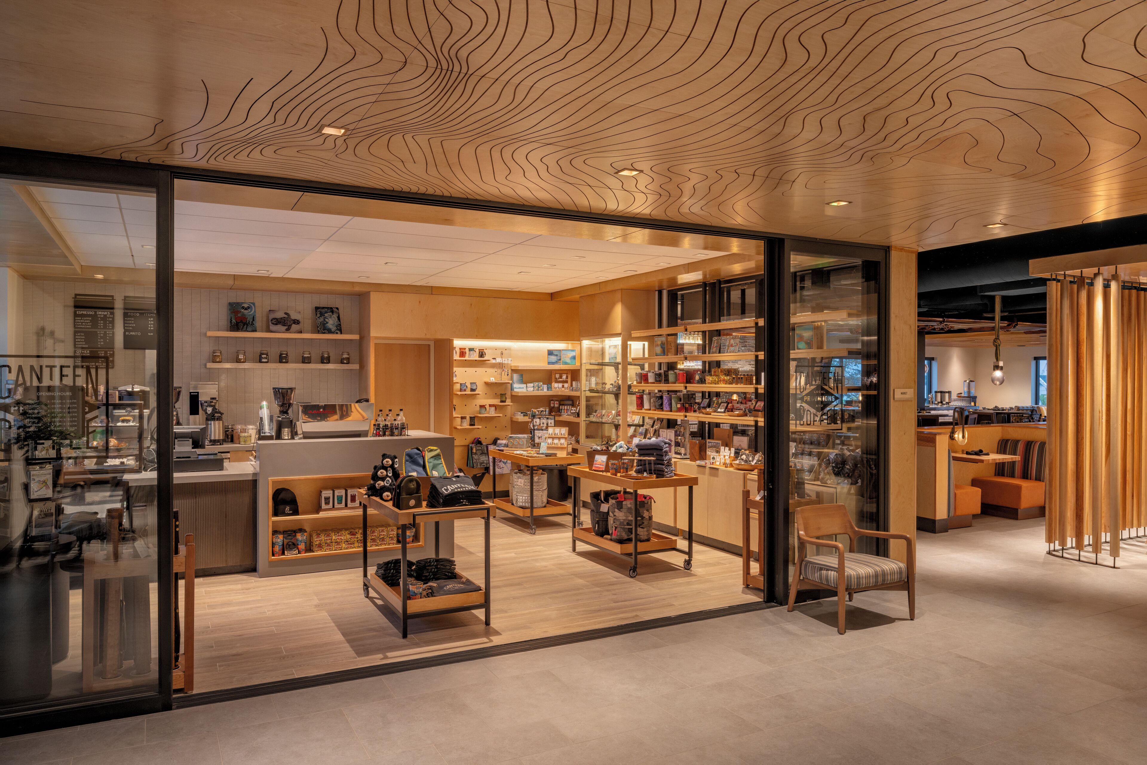 A modern interior with a wooden ceiling, glass storefront, and various retail displays.