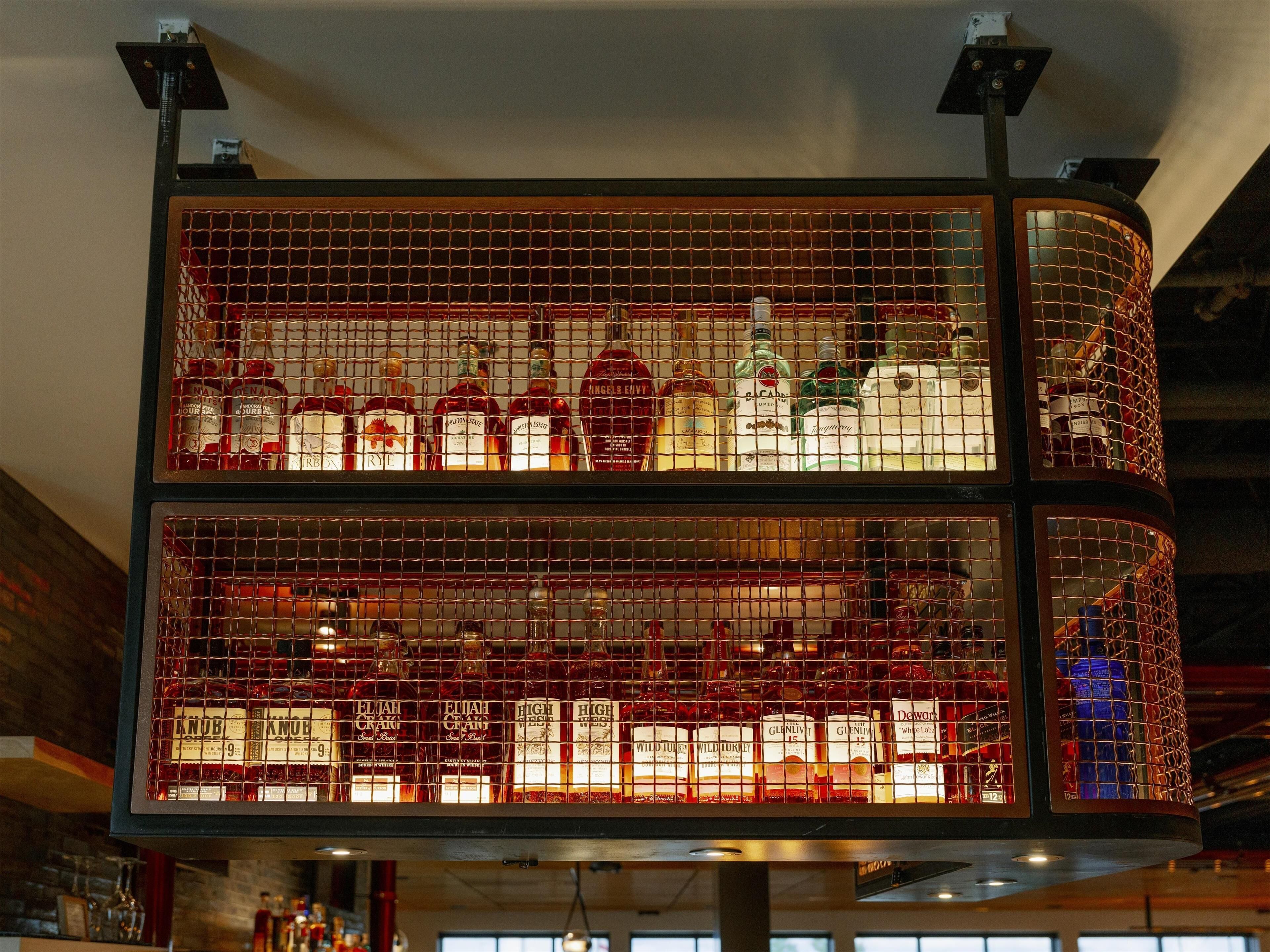A bar area with a grid-like structure containing various bottles of liquor.