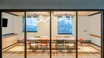 A modern meeting room with a large table, colorful chairs, and large windows with a view.