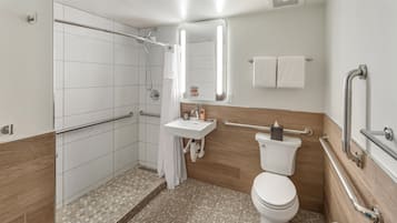 Een moderne badkamer met douche, toilet en wastafel. Er zijn handgrepen en een handrail voor toegankelijkheid.