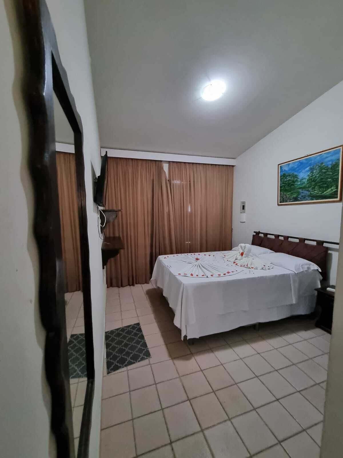 Un dormitorio con cama, cortinas, un cuadro y piso de baldosas.