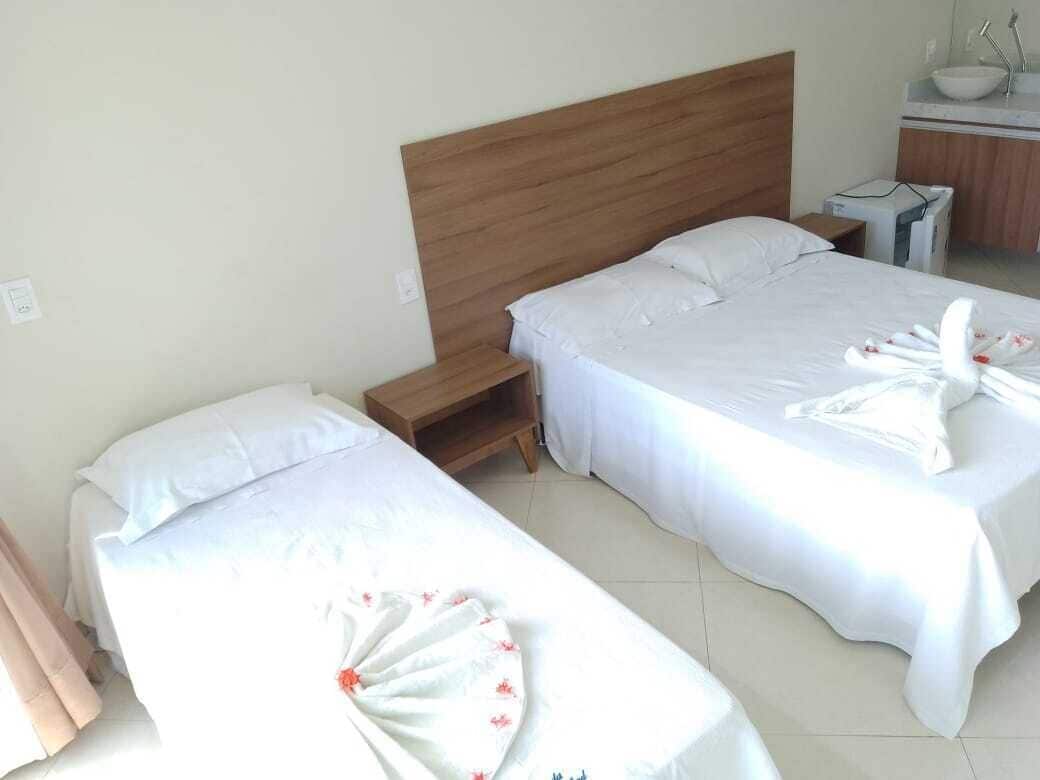Two single beds with wooden headboards, a small bedside table, and a bathroom with a sink and mirror.