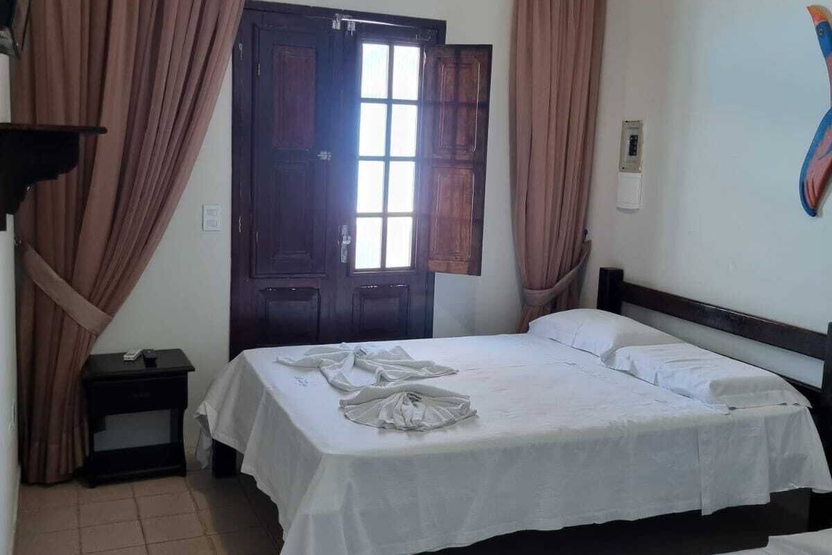 Habitació d'hotel amb dos llits, una porta de fusta, una petita taula de nit i una làmpada fixa a la paret.