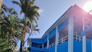 A two-story building with a blue and white color scheme, a reception area, and a paved entrance. - Morada Azul (Ipojuca)