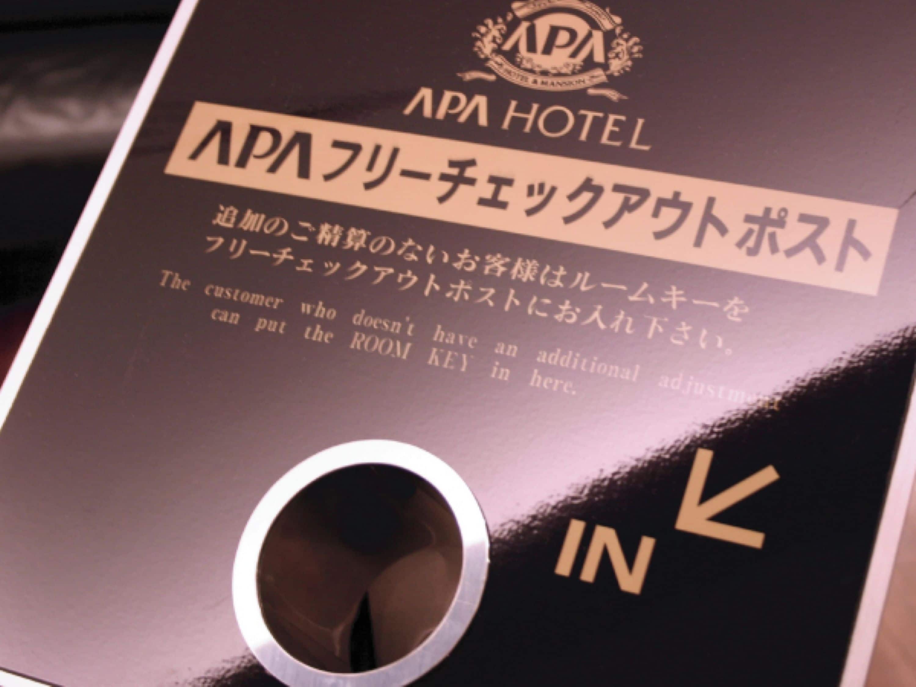 A sign with the text "APA HOTEL" and instructions for room key placement.