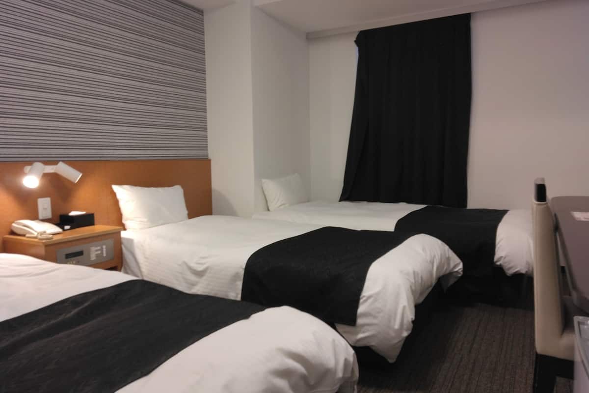 Une chambre d’hôtel avec deux lits, un bureau, une table de chevet et une lampe.