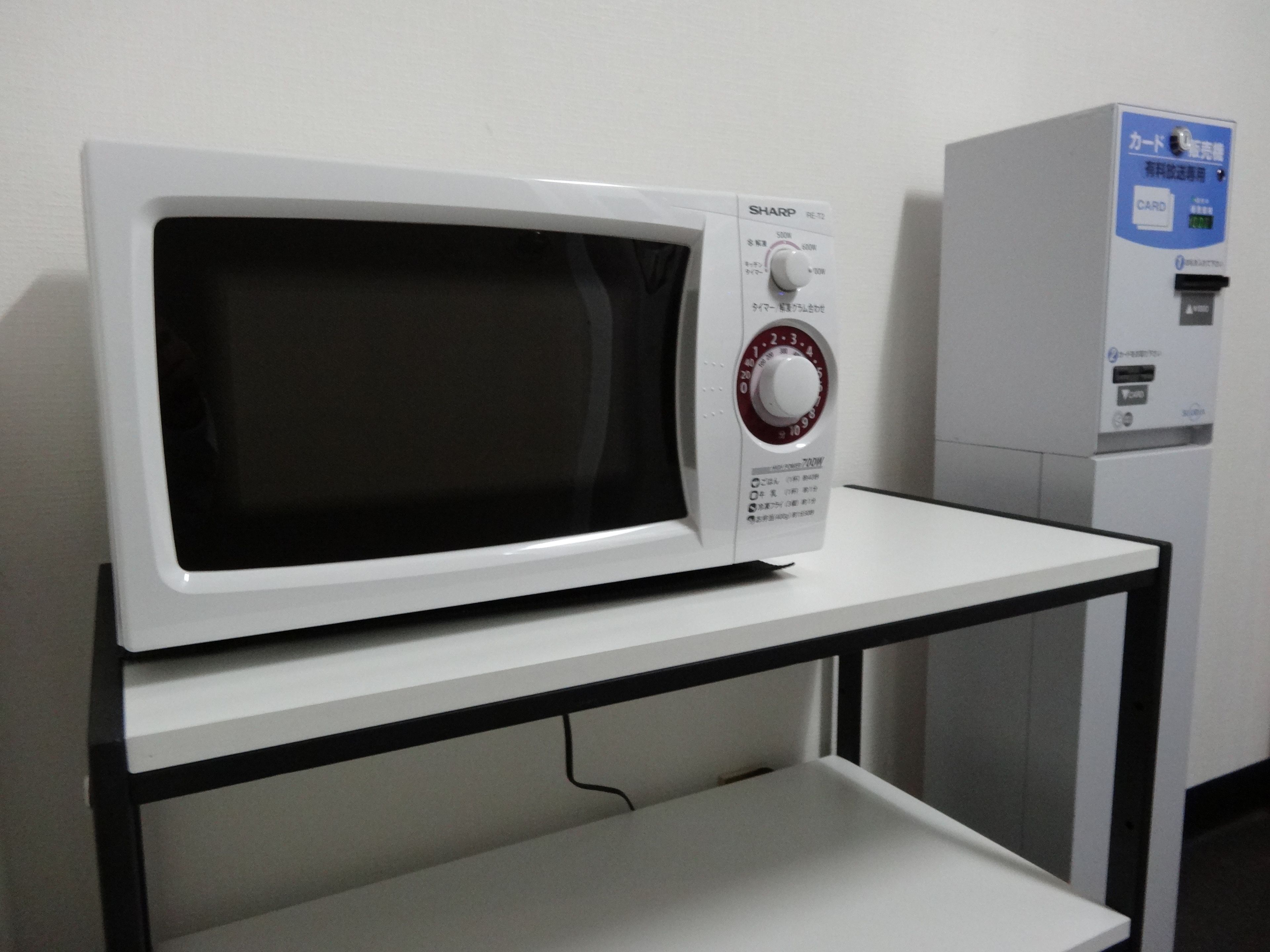 Un four à micro-ondes blanc, avec un panneau de commande, posé sur une table blanche.