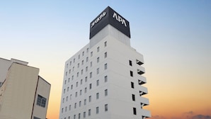 Een hotel met meerdere verdiepingen en een opvallend APA-bord bovenop.