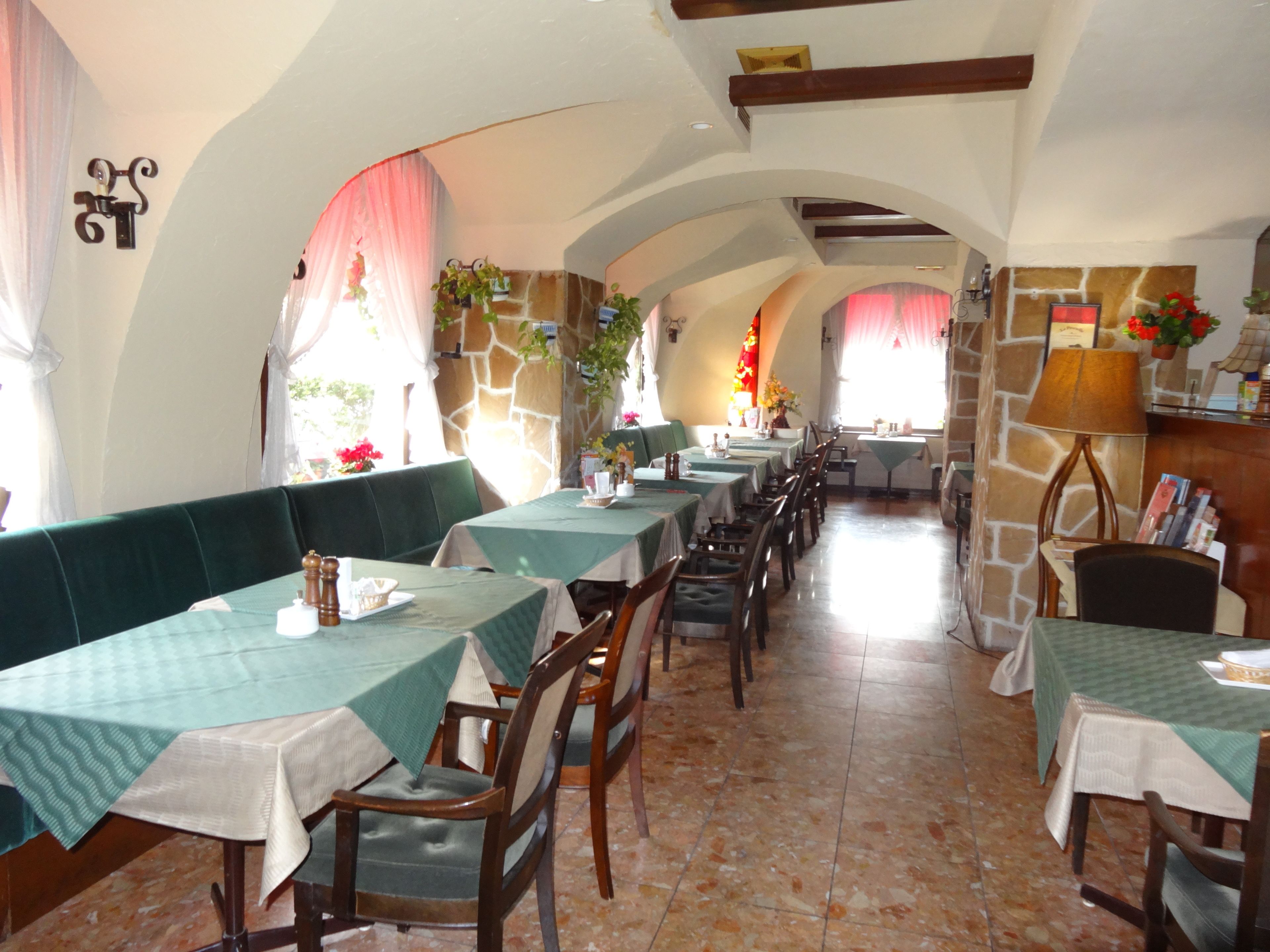A restaurant with multiple tables and booths, stone walls, and arched ceilings.