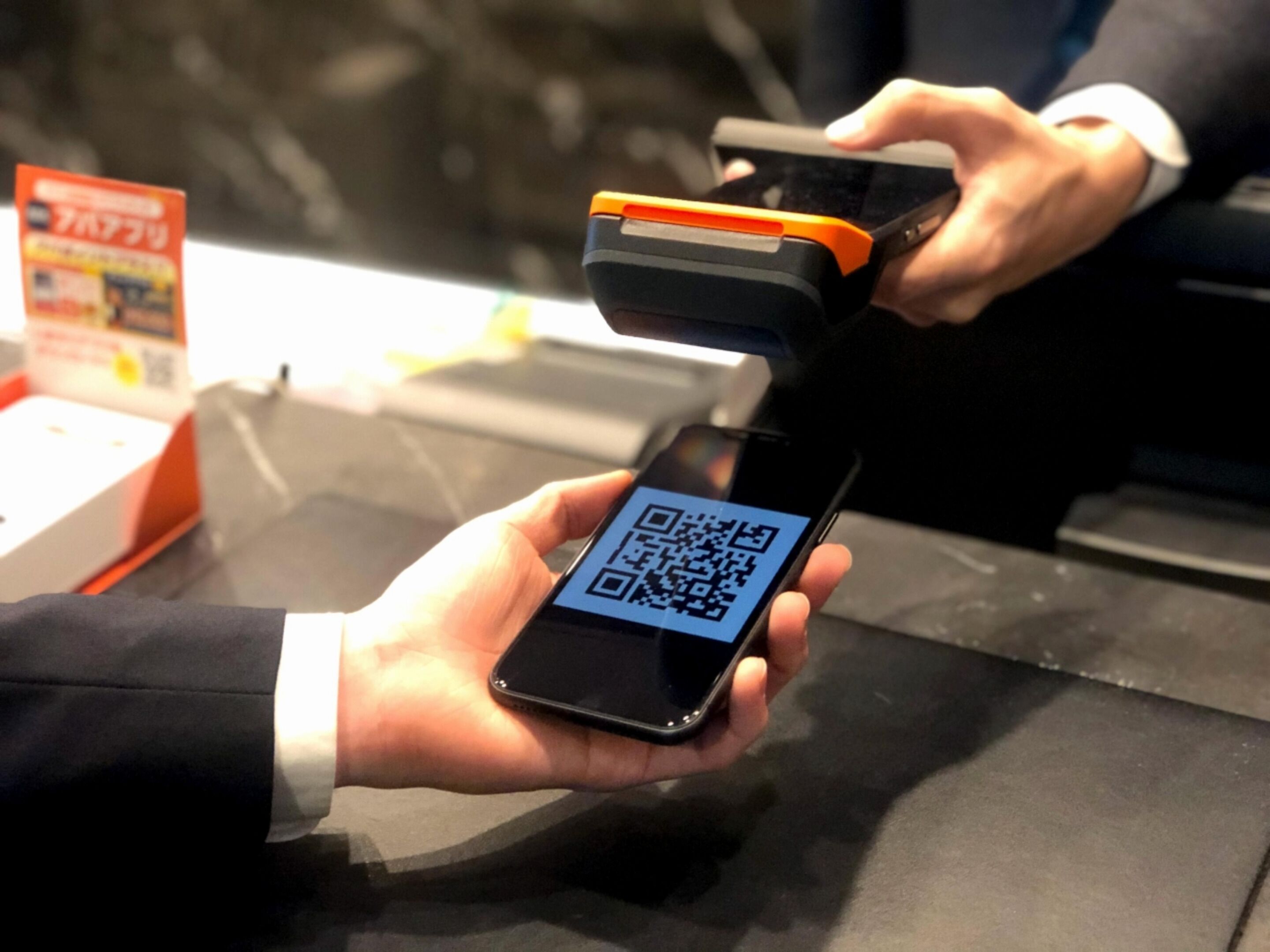 A person holding a smartphone with a QR code displayed on the screen.