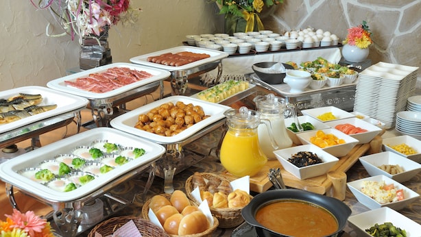 Een buffet met diverse gerechten, waaronder vlees, fruit en groenten.