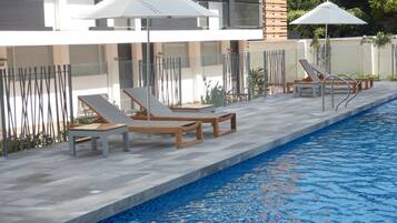 Una piscina al aire libre, sillones reclinables de piscina