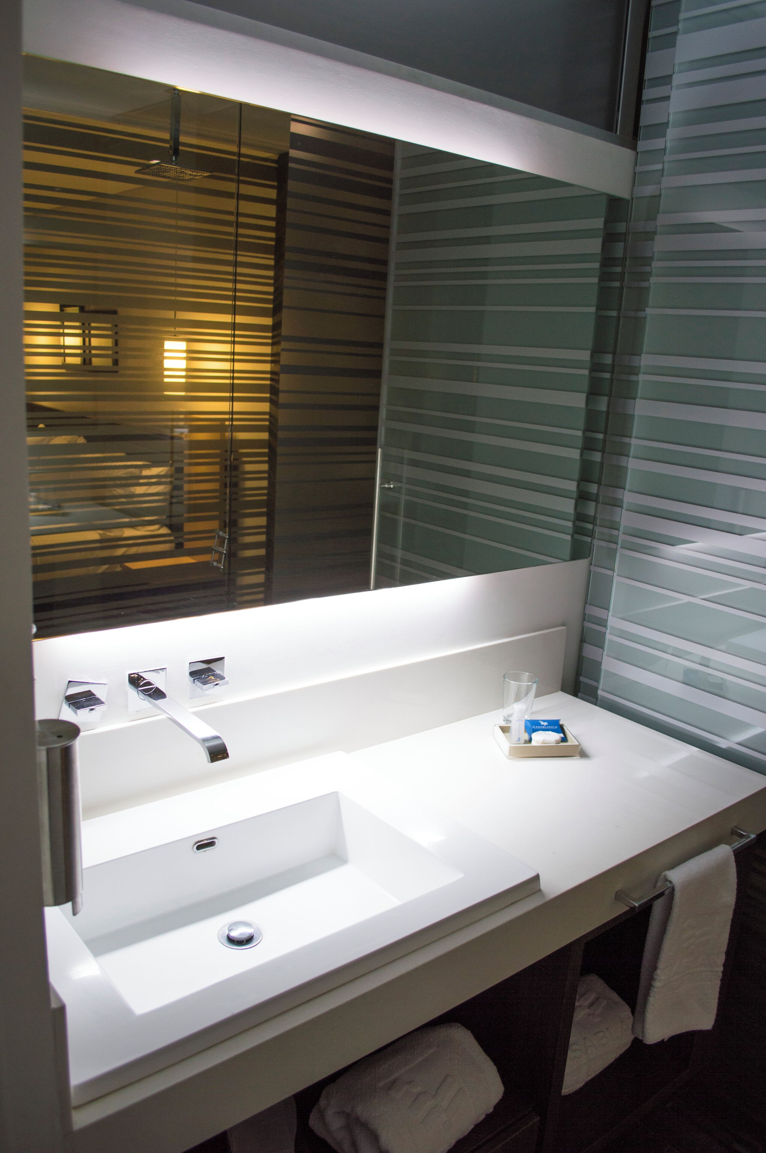 A modern bathroom with a large mirror, a white sink, and a glass shower enclosure.