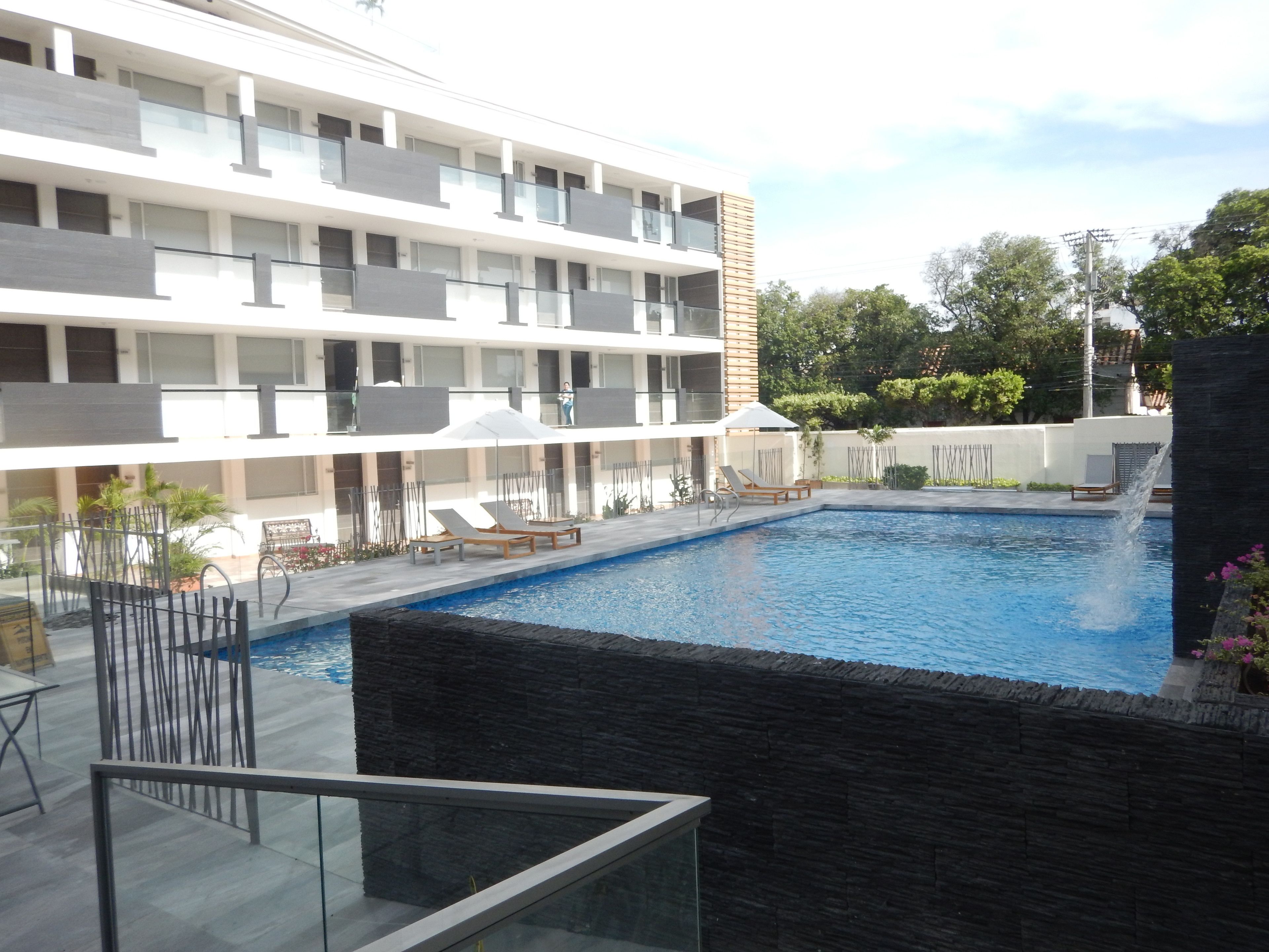 A modern hotel with a swimming pool, multiple balconies, and outdoor seating areas.