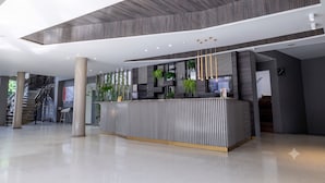 A modern reception area with a central counter, vertical wooden slats, and a staircase in the background. - Hotel Casa Blanca (San José de Cúcuta)