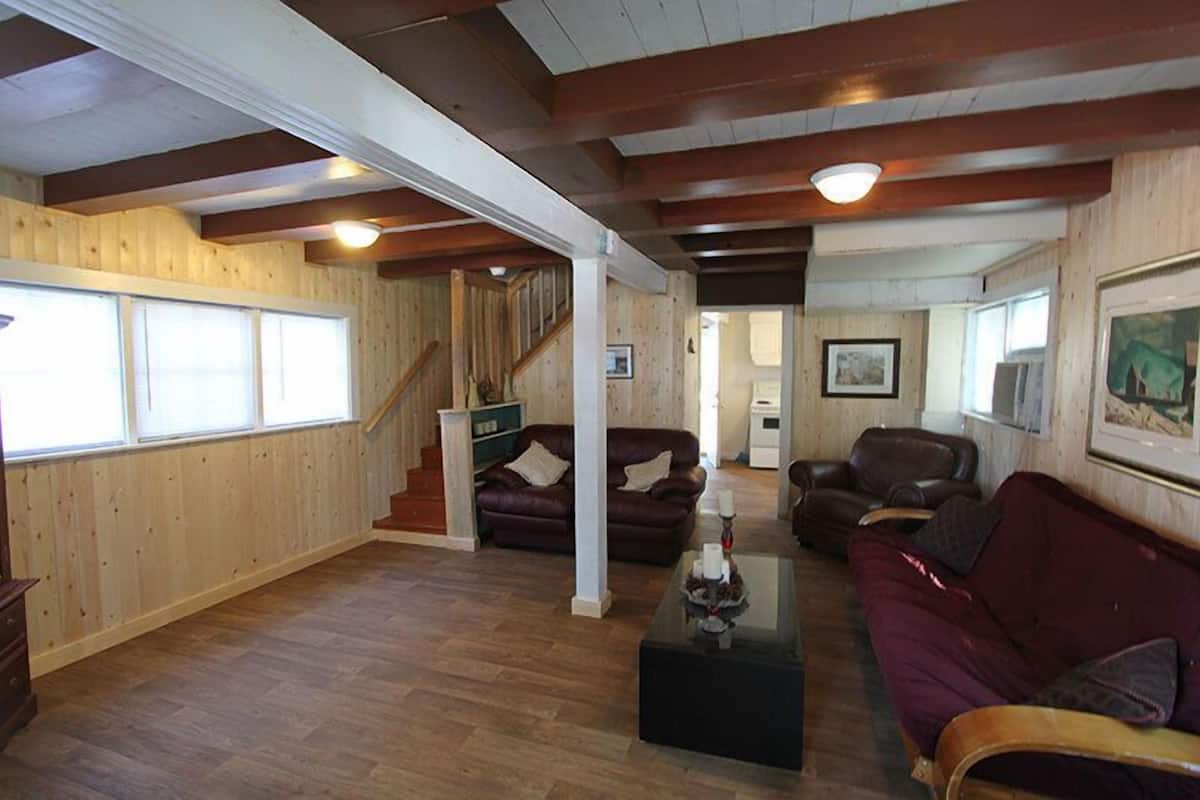 Ein geräumiges Wohnzimmer mit Holzböden, einer Treppe und einem großen Fenster.