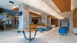 A spacious lobby with a modern design, featuring a central round table, blue seating, and a staircase leading to an upper level. - Crowne Plaza Kayseri by IHG (Kayseri)