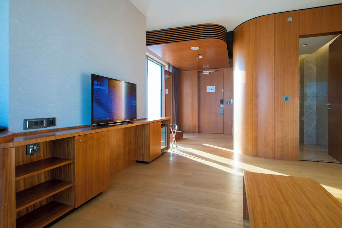 Una habitación de hotel moderna con un tocador de madera, un televisor de pantalla plana y un espejo grande.