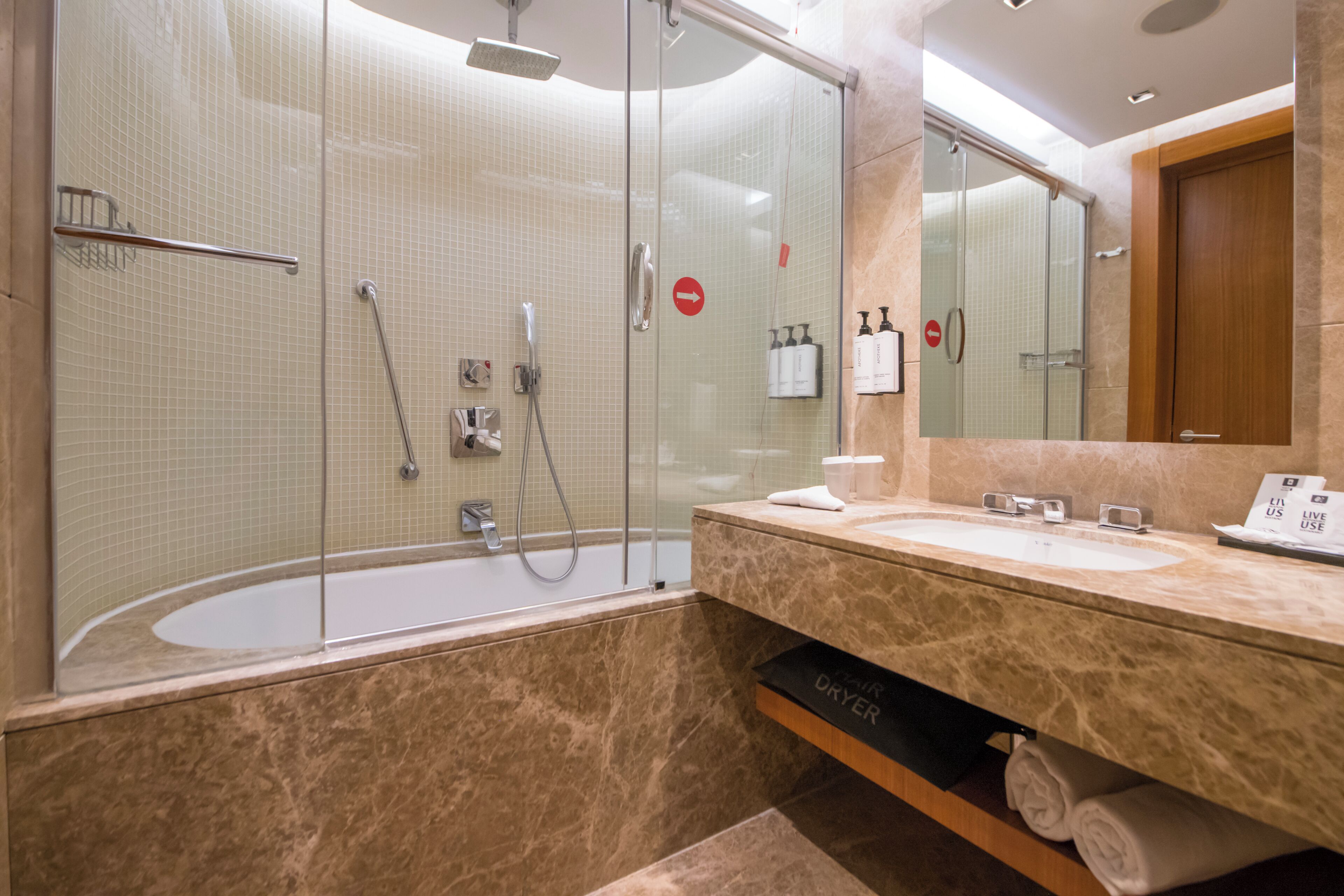 A modern bathroom with a glass-enclosed shower, a bathtub, and a vanity with a mirror.