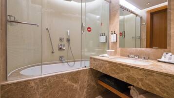 A modern bathroom with a glass-enclosed shower, a bathtub, and a vanity with a mirror.