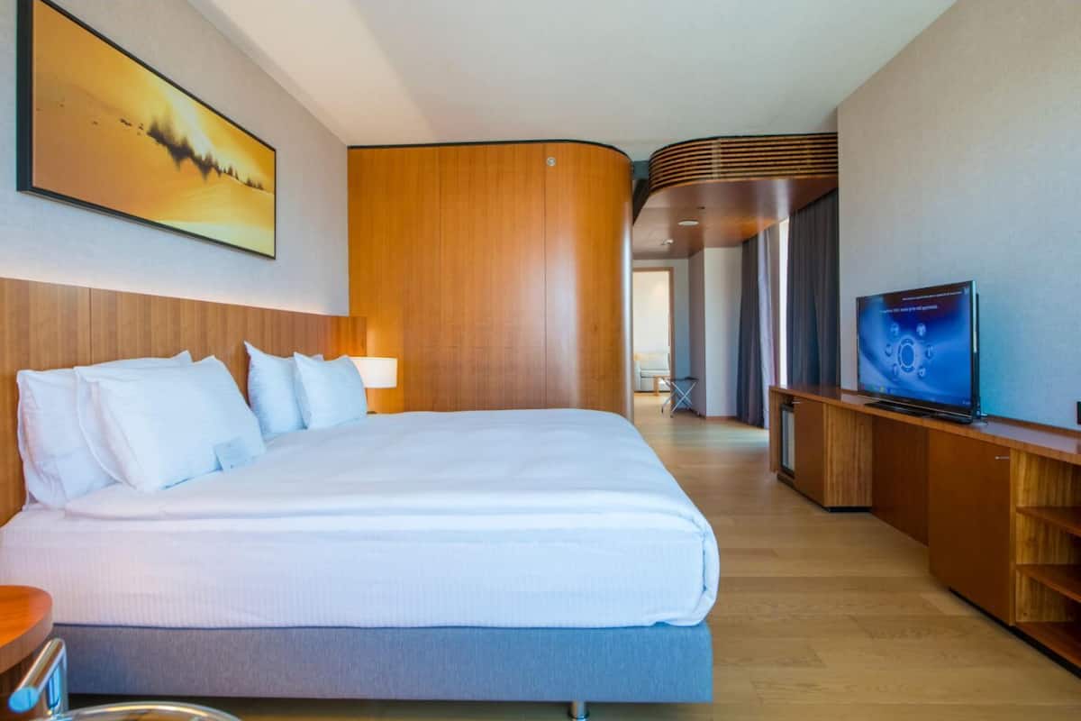 Una habitación de hotel con una cama grande, televisión y un cuadro en la pared.