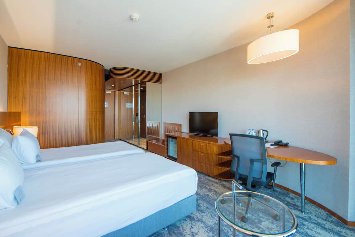 Una habitación de hotel con cama, escritorio, televisión y zona de estar.