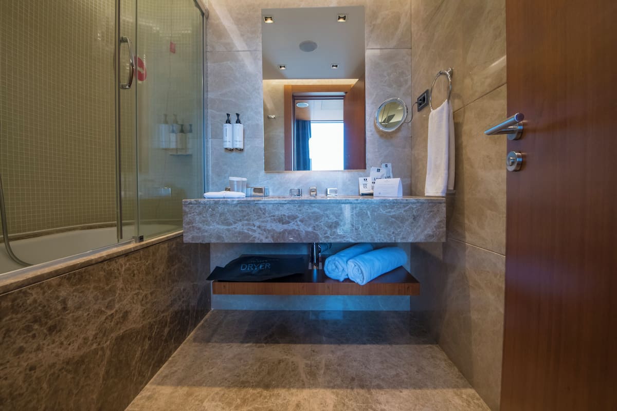 Un baño moderno con cabina de ducha de vidrio, lavamanos de mármol y espejo integrado.