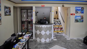 A reception area with a counter, a computer, and a staircase leading to an upper floor. - Pousada Veleiro de Porto (Ipojuca)