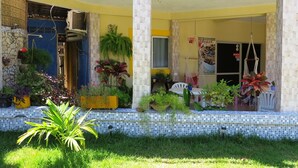 A building with a tiled porch, outdoor seating, and various potted plants. - Pousada Veleiro de Porto (Ipojuca)