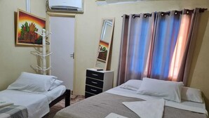 A hotel room with two single beds, a dresser, a mirror, and a painting of fruits. - Pousada Veleiro de Porto (Ipojuca)
