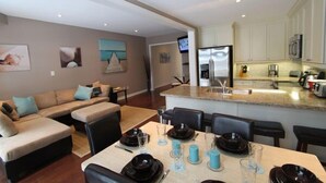 A modern kitchen with white cabinets, a built-in microwave, and a stainless steel refrigerator. - Beachfront Beach Houses (Wasaga Beach)