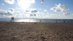 A beach with people, a sign, and kites flying in the sky. - Beachfront Beach Houses (Wasaga Beach)