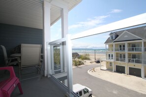 A balcony with a view of a beach and a building with multiple garages.