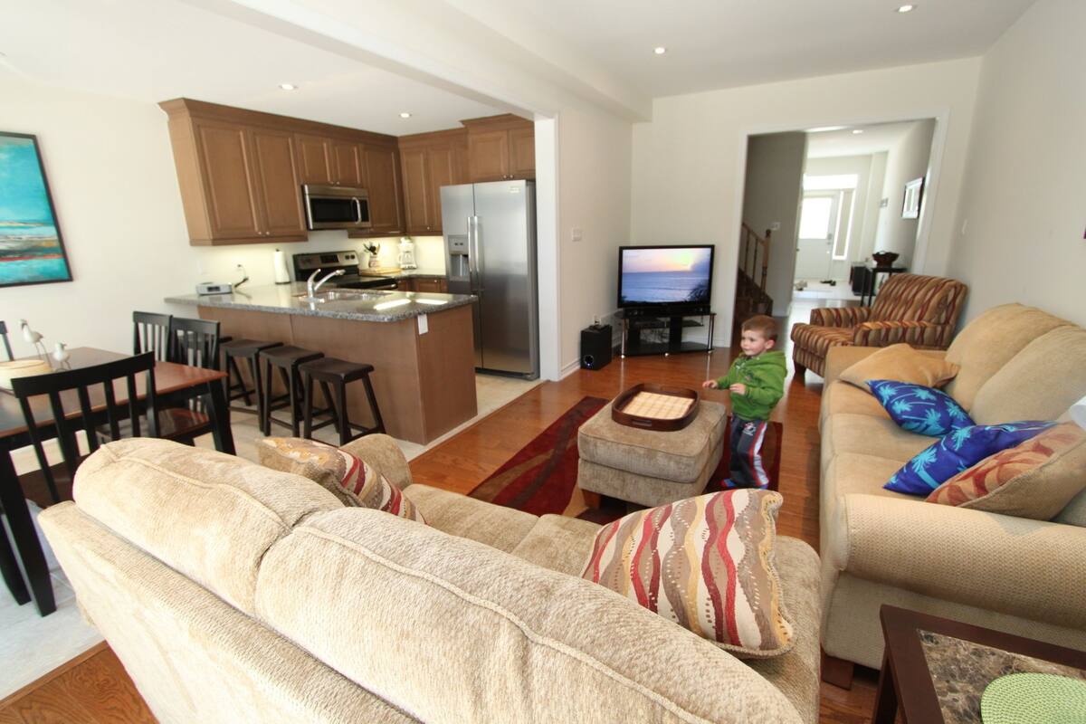 A modern living room with a sofa, ottoman, and a television.