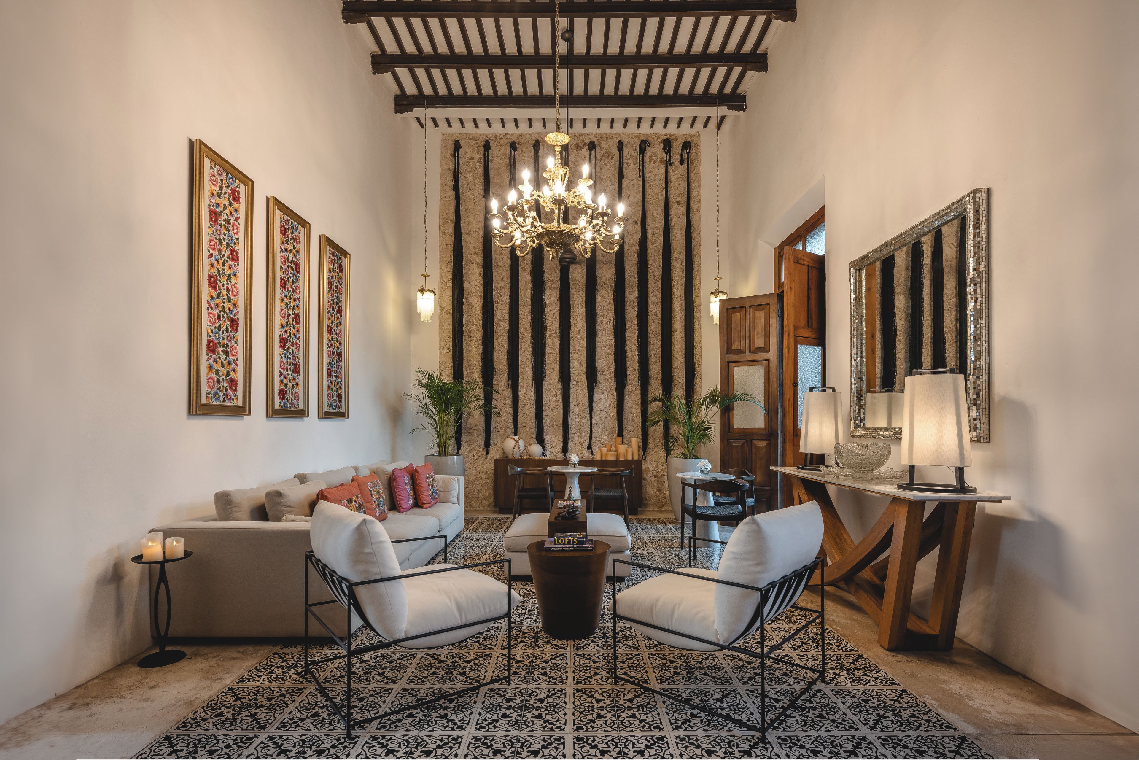 Uma sala de estar ampla com teto alto, um lustre, um sofá e uma mesa de centro.