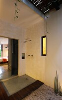 Un baño moderno con ducha, una ventana pequeña y una puerta que da a otra habitación.