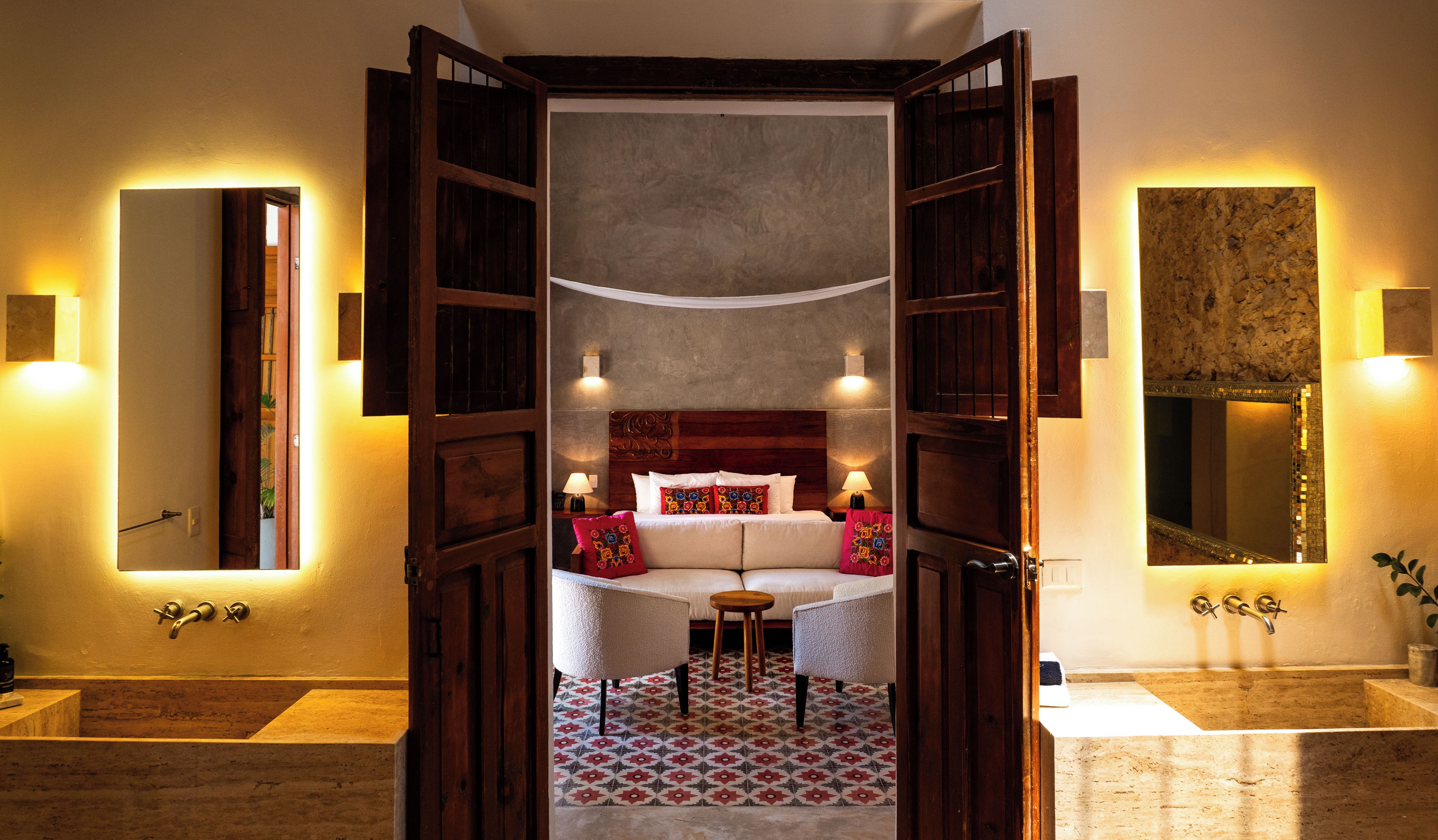 A hotel room with a large bed, two bedside tables, a small round table, and a bathroom with a bathtub and sink.