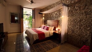 A bedroom with a bed, nightstand, lamp, and a stone wall. - Casa de Las Palomas by Palomas Hotels -  Adults only (Mérida)