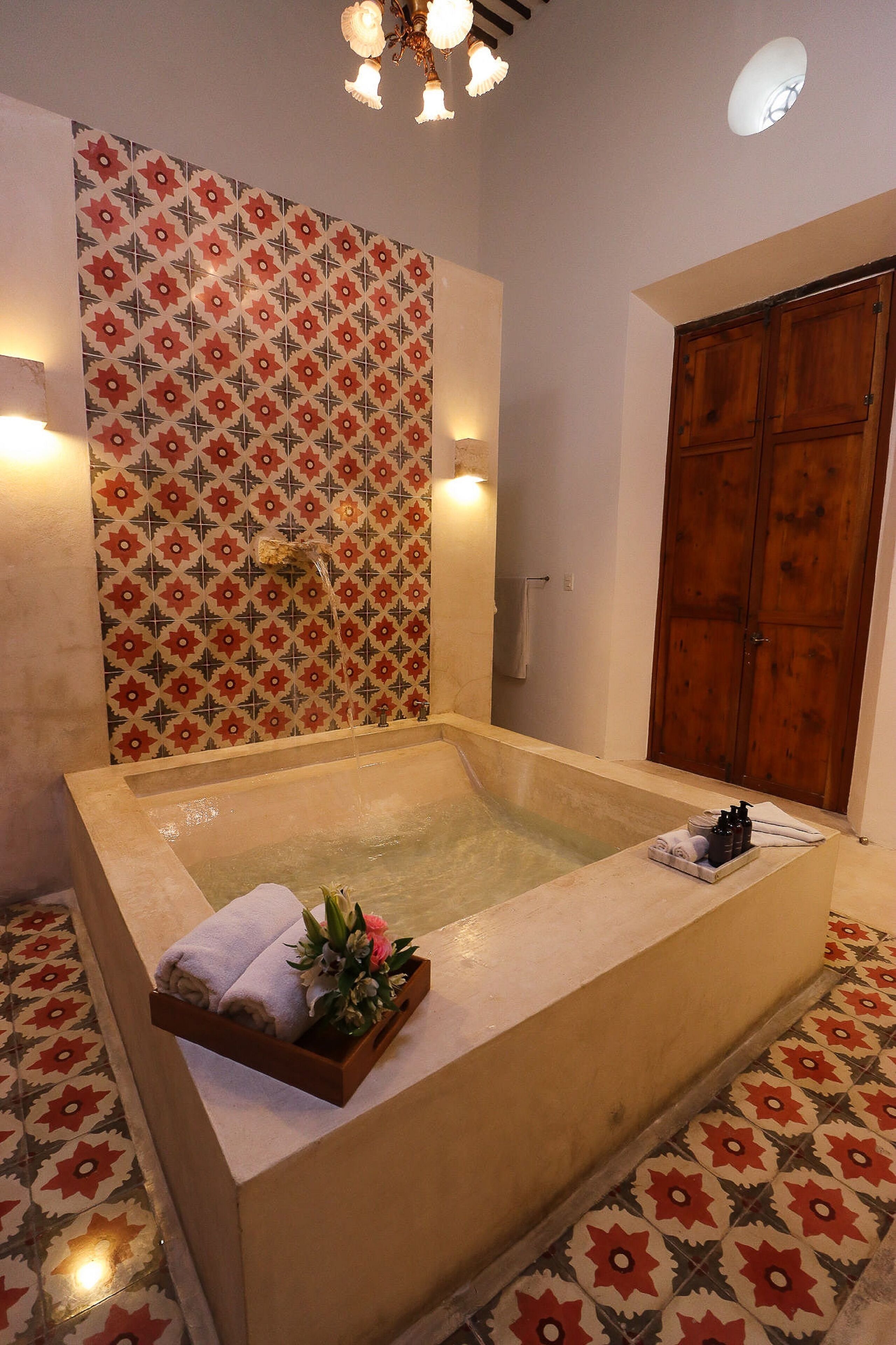 Un baño amplio con una bañera grande, una puerta de madera y azulejos estampados en las paredes y el suelo.