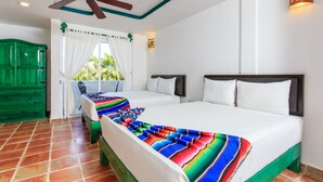 Habitació d'hotel amb dos llits, un ventilador de sostre, un taulell verd i una finestra amb cortines.