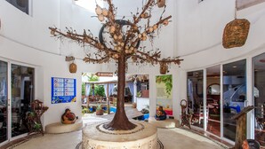 Un amplitudós atrium amb una escultura d'arbre central, una zona de recepció i diversos elements decoratius.