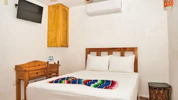 Un dormitorio con una cama, una mesita de noche de madera, un televisor y un equipo de aire acondicionado.