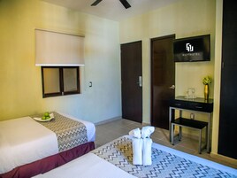 Una habitación de hotel con dos camas, un escritorio con espejo, televisión y minibar.