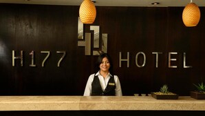 A hotel reception desk with the sign "H177 HOTEL" and two hanging lamps. - H177 Hotel (Campeche)