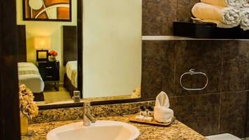 A bathroom with a granite countertop, a white sink, a mirror, and a towel rack.