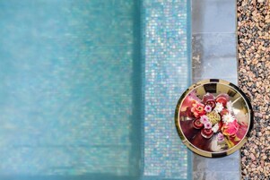Una mesa redonda con un arreglo floral al lado de una piscina.