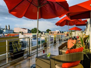 A rooftop terrace with red umbrellas, wicker furniture, and potted plants. - H177 Hotel (Campeche)