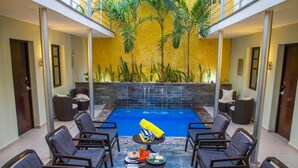 A pool area with lounge chairs and a dining table, surrounded by a yellow wall and palm trees. - H177 Hotel (Campeche)