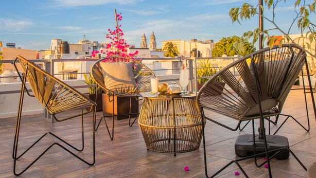 A rooftop terrace with wicker chairs, a table, and a potted plant. - H177 Hotel (Campeche)